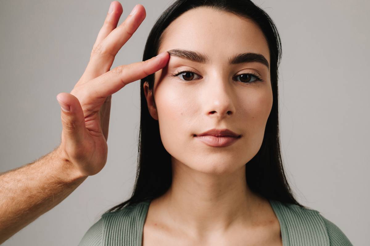 woman with hand pressing against eyelid for blog about eyelid surgery recovery tips